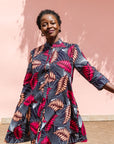 Model wearing a navy dress with red and peach feather print.
