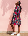 Model wearing a navy dress with red and peach feather print.