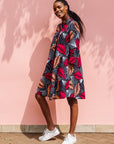 Model wearing a navy dress with red and peach feather print.