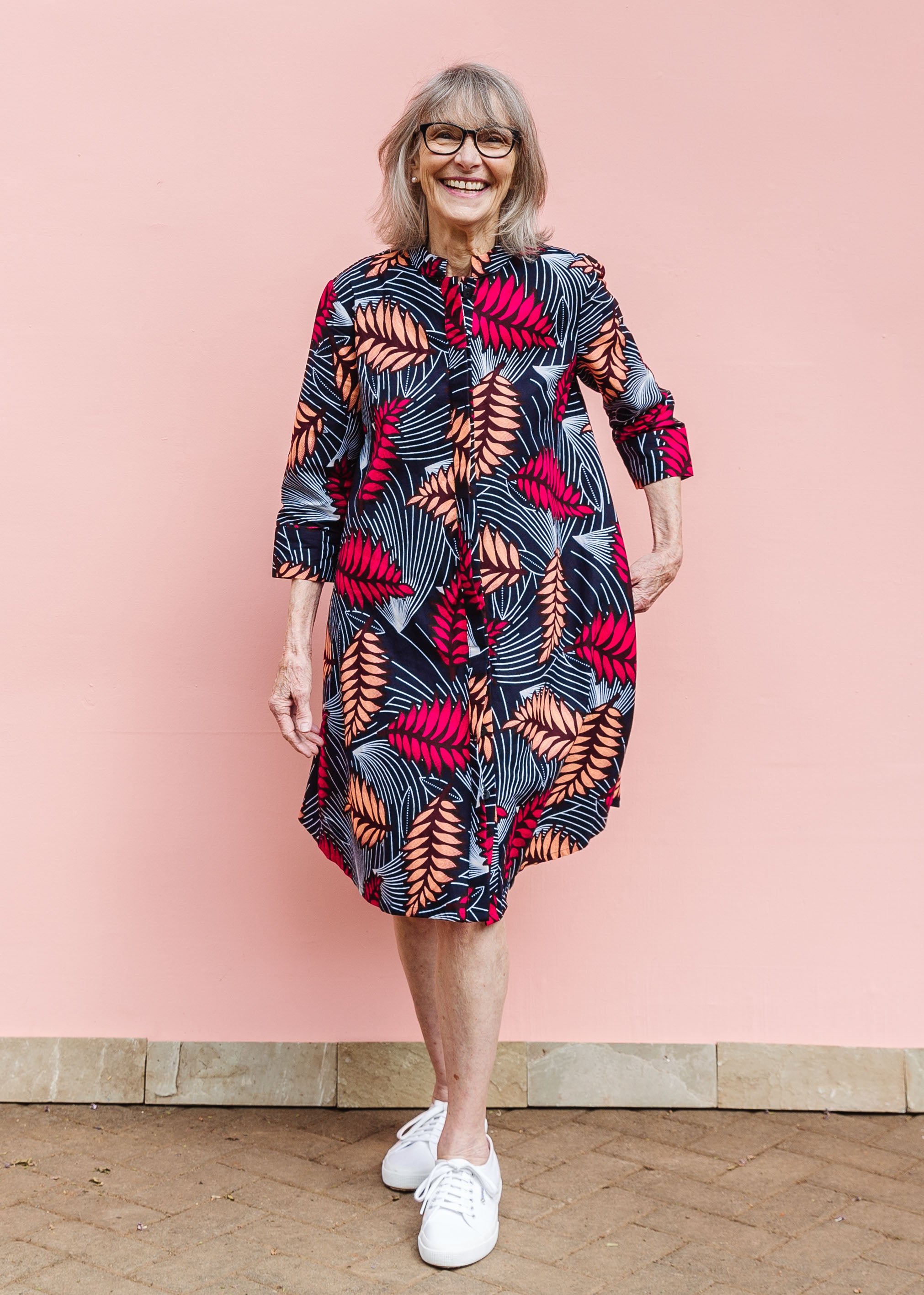 Model wearing a navy dress with red and peach feather print.
