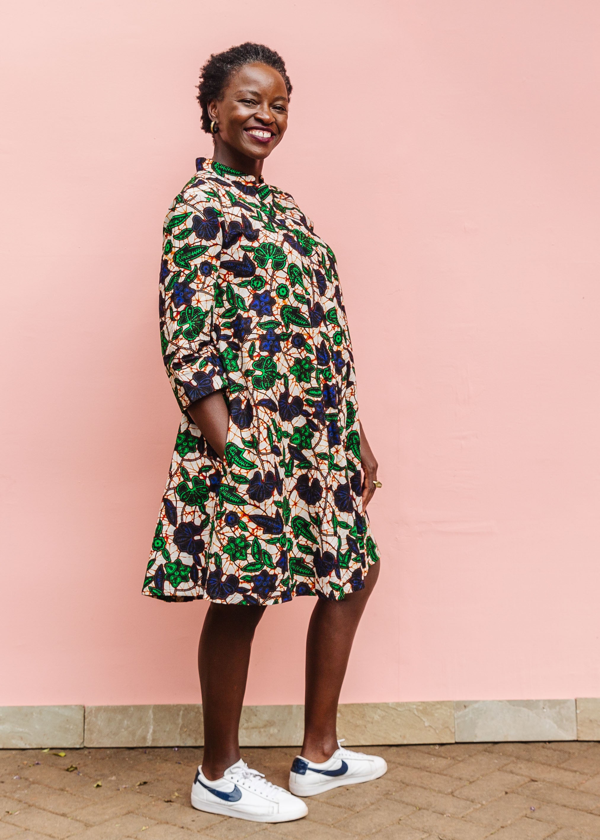 Model wearing brown dress with green and blue vine print.