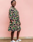 Model wearing brown dress with green and blue vine print.