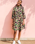 Model wearing brown dress with green and blue vine print.