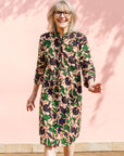 Model wearing brown dress with green and blue vine print.