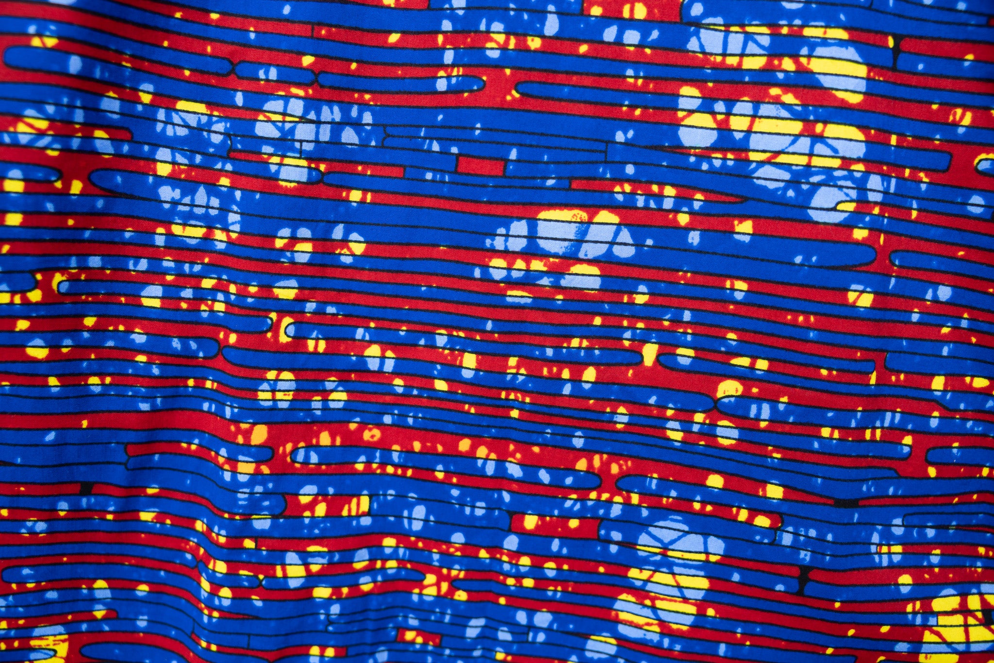 Close up display of a red and blue graphic print sleeveless dress.