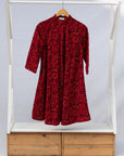 Display of red dress with small black and yellow branch design.