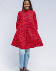 Model wearing red dress with small black and yellow branch design.