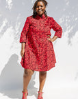Model wearing red dress with small black and yellow branch design.