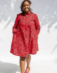 Model wearing red dress with small black and yellow branch design.