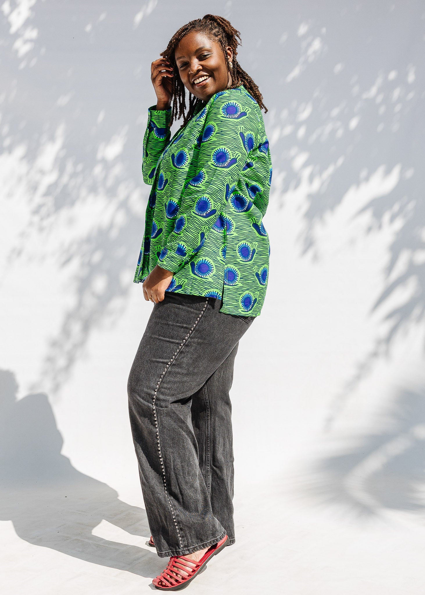 Model wearing green and blue snail print, long sleeved shirt.