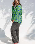 Model wearing green and blue snail print, long sleeved shirt.