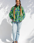 Model wearing green and blue snail print, long sleeved shirt.