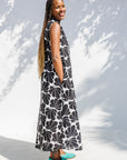 Model wearing black and white floral print, sleeveless dress.