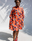 Model wearing yellow and red, blue book print dress.
