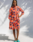 Model wearing yellow and red, blue book print dress.