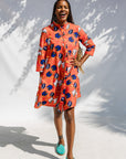 Model wearing yellow and red, blue book print dress.
