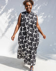 Model wearing black and white floral print, sleeveless dress.