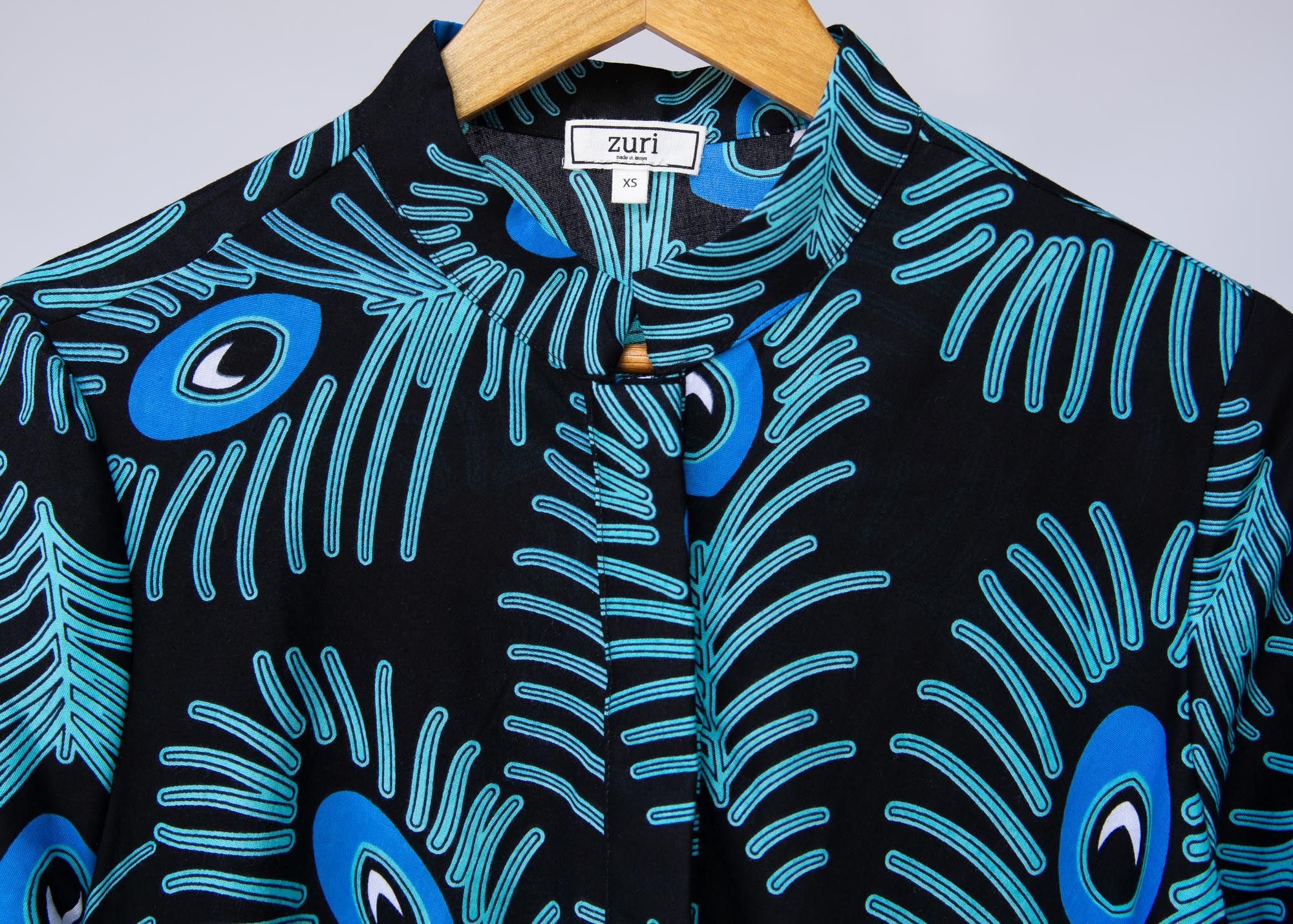 Display of black dress with blue, white and turquoise peacock feather design print