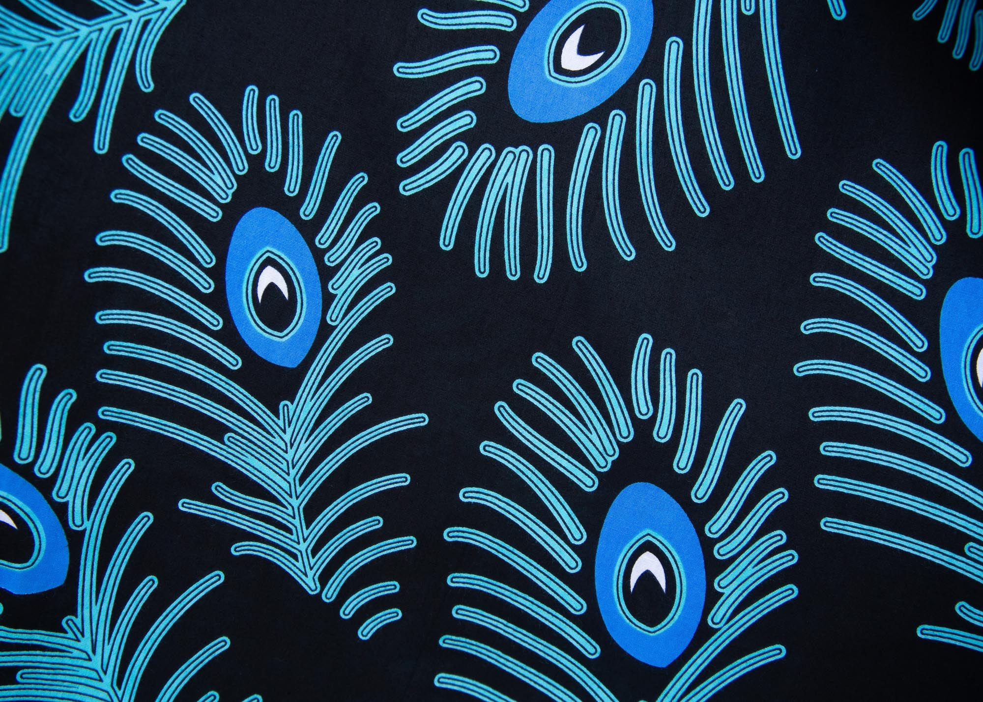 Close up display of black dress with blue, white and turquoise peacock feather design print