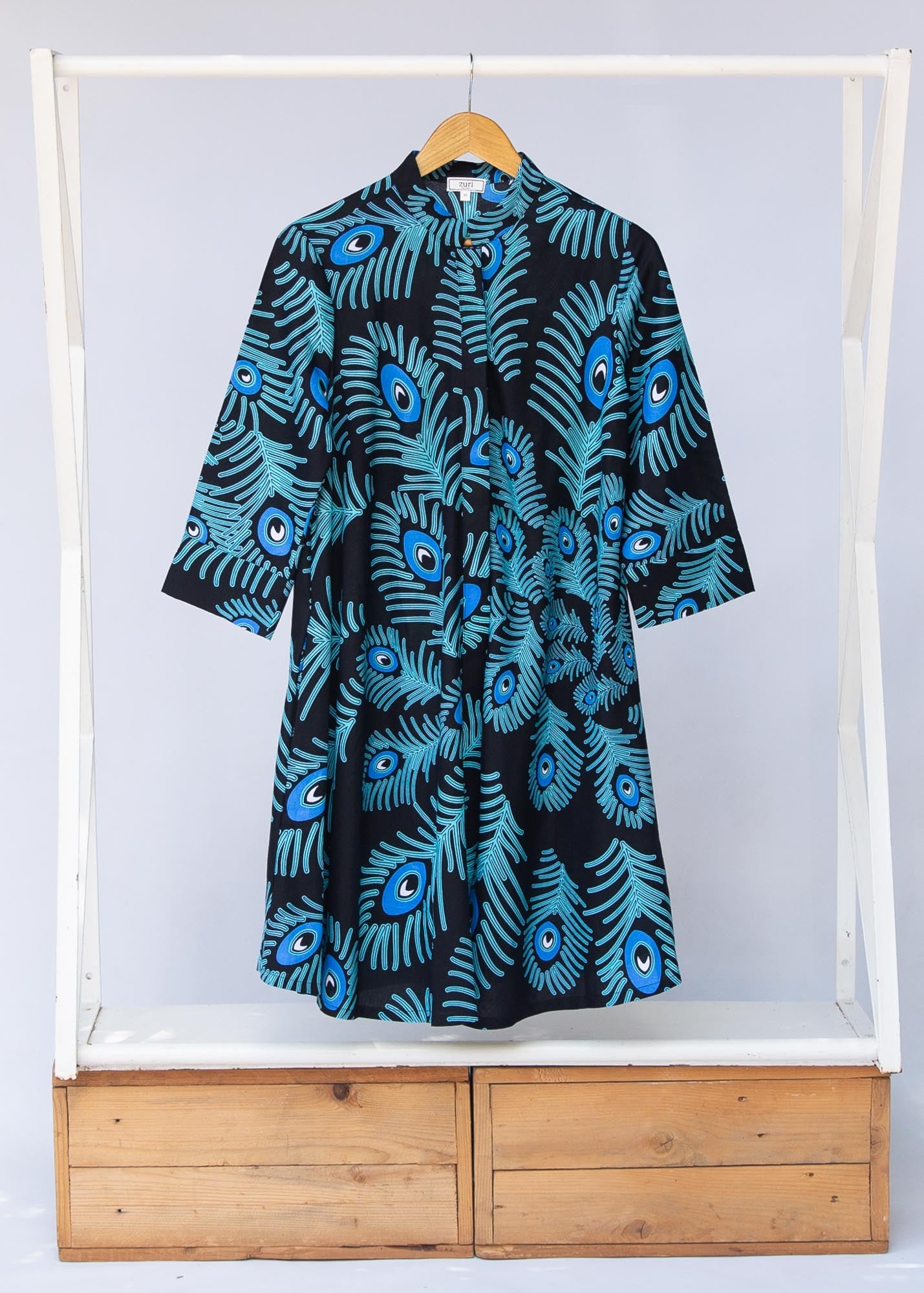 Display of black dress with blue, white and turquoise peacock feather design print
