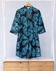Display of black dress with blue, white and turquoise peacock feather design print