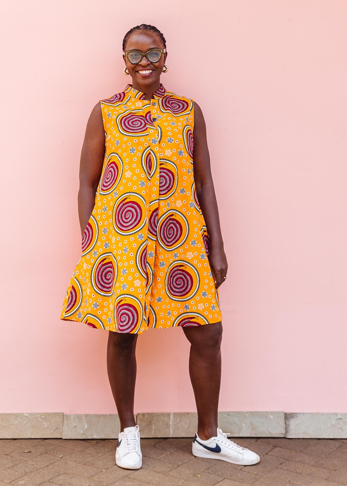 The model is wearing orange white, black and burgundy snail design dress