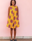 The model is wearing orange white, black and burgundy snail design dress