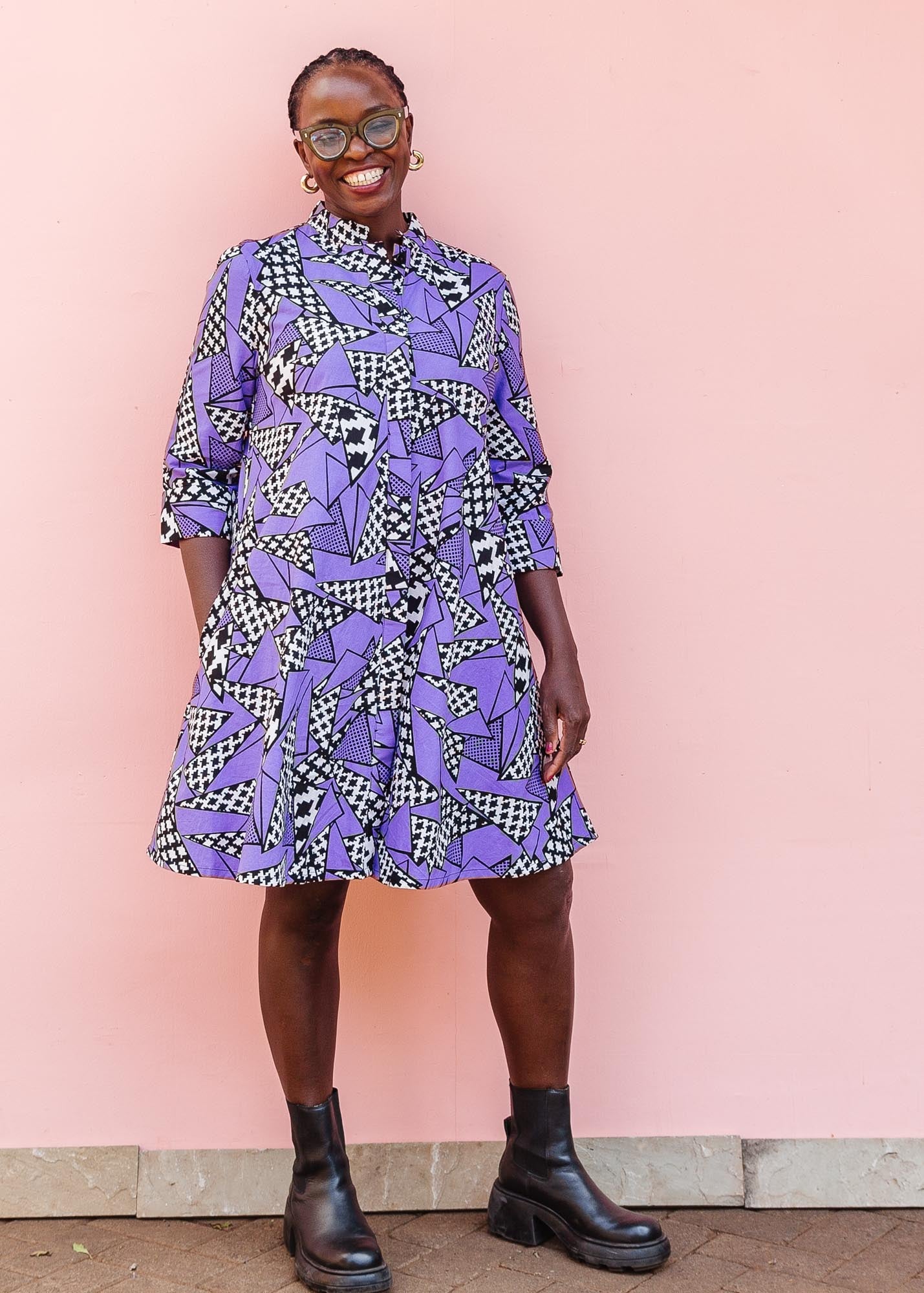The model is wearing purple, black and white geometric print dress