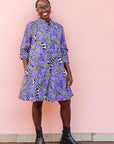 The model is wearing purple, black and white geometric print dress