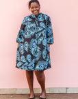 The model is wearing a black dress with blue, white and turquoise peacock feather design print