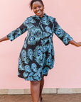 The model is wearing a black dress with blue, white and turquoise peacock feather design print