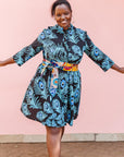 The model is wearing a black dress with blue, white and turquoise peacock feather design print