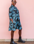 The model is wearing a black dress with blue, white and turquoise peacock feather design print   