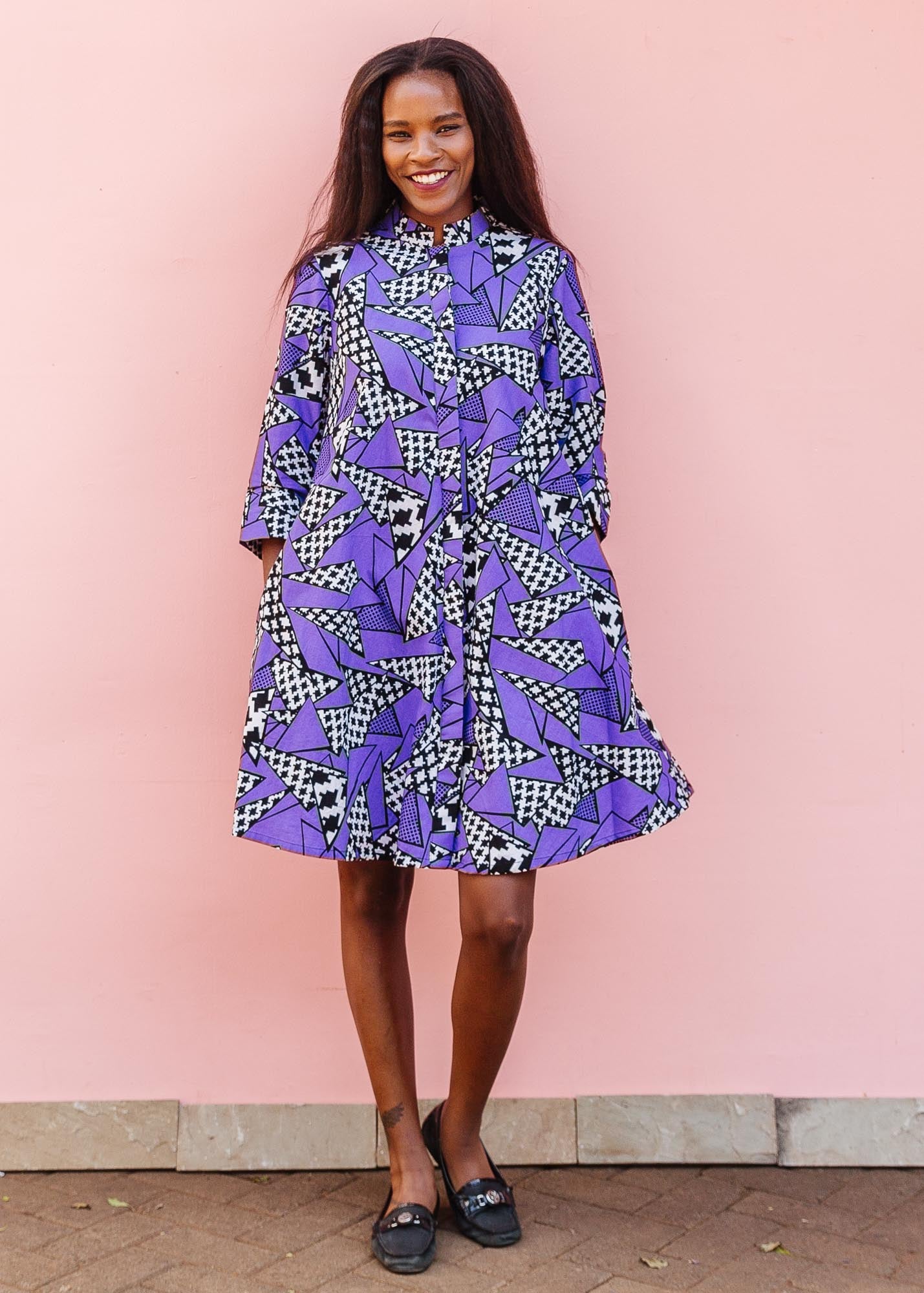 The model is wearing purple, black and white geometric print dress