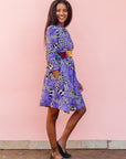 The model is wearing purple, black and white geometric print dress