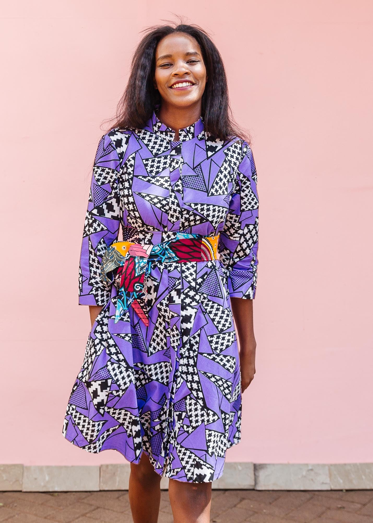 The model is wearing purple, black and white geometric print dress