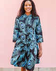 The model is wearing a black dress with blue, white and turquoise peacock feather design print