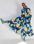 Model wearing blue, black, orange, yellow, orange and white geometric print shirt and culotte.