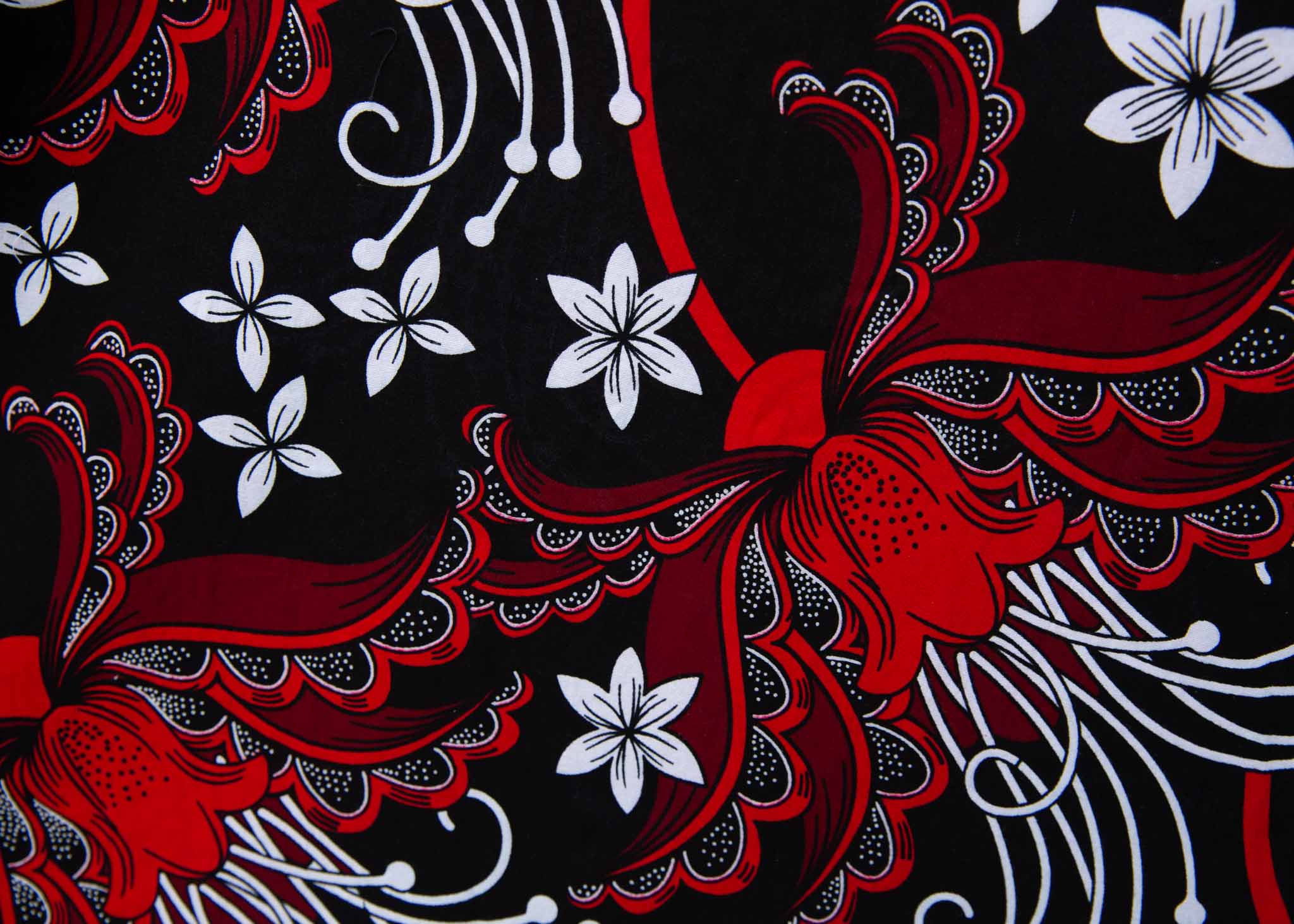 Display of black dress with red and white flowers, fabric.