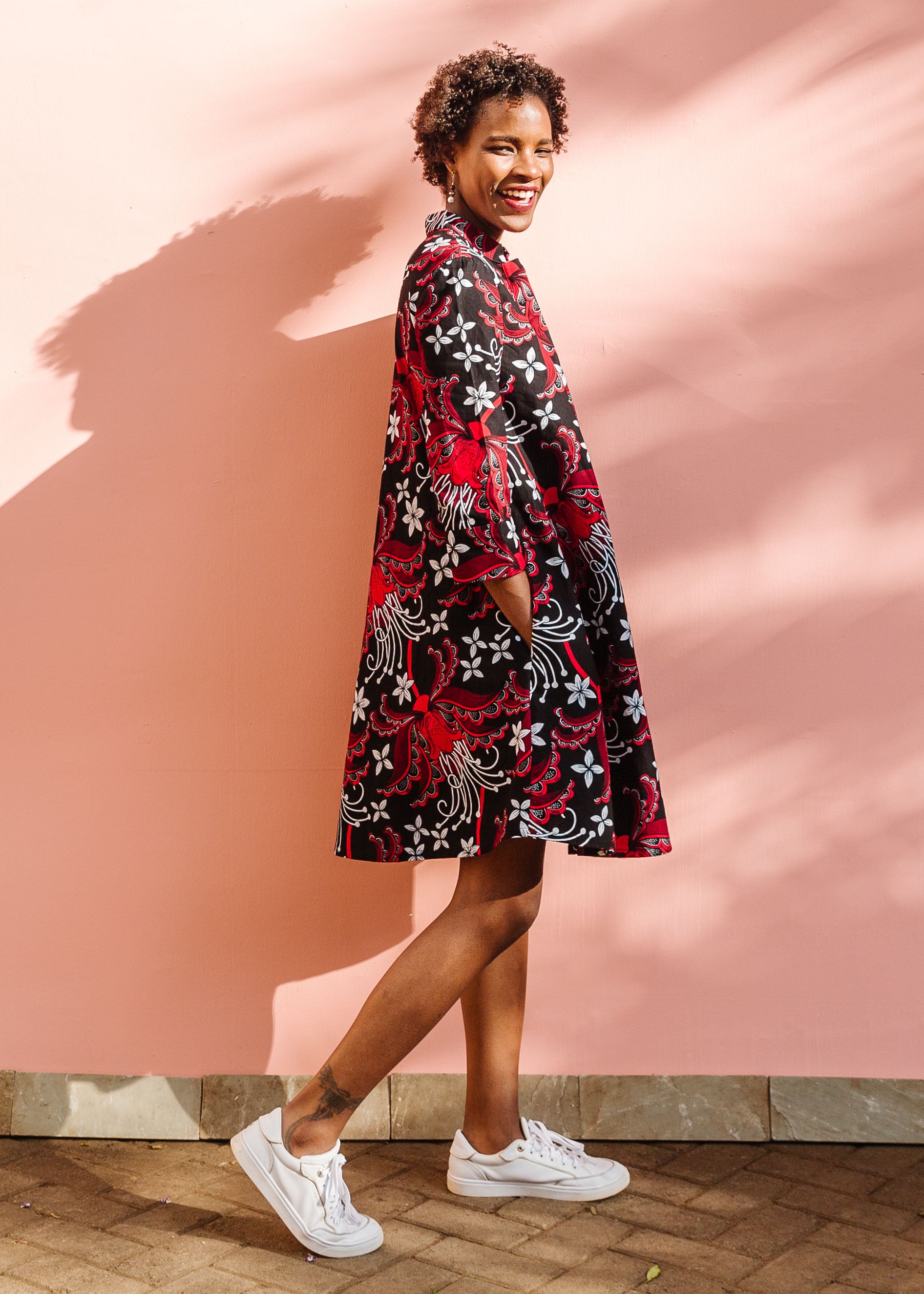 Model wearing black dress with red and white flowers.