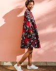 Model wearing black dress with red and white flowers.