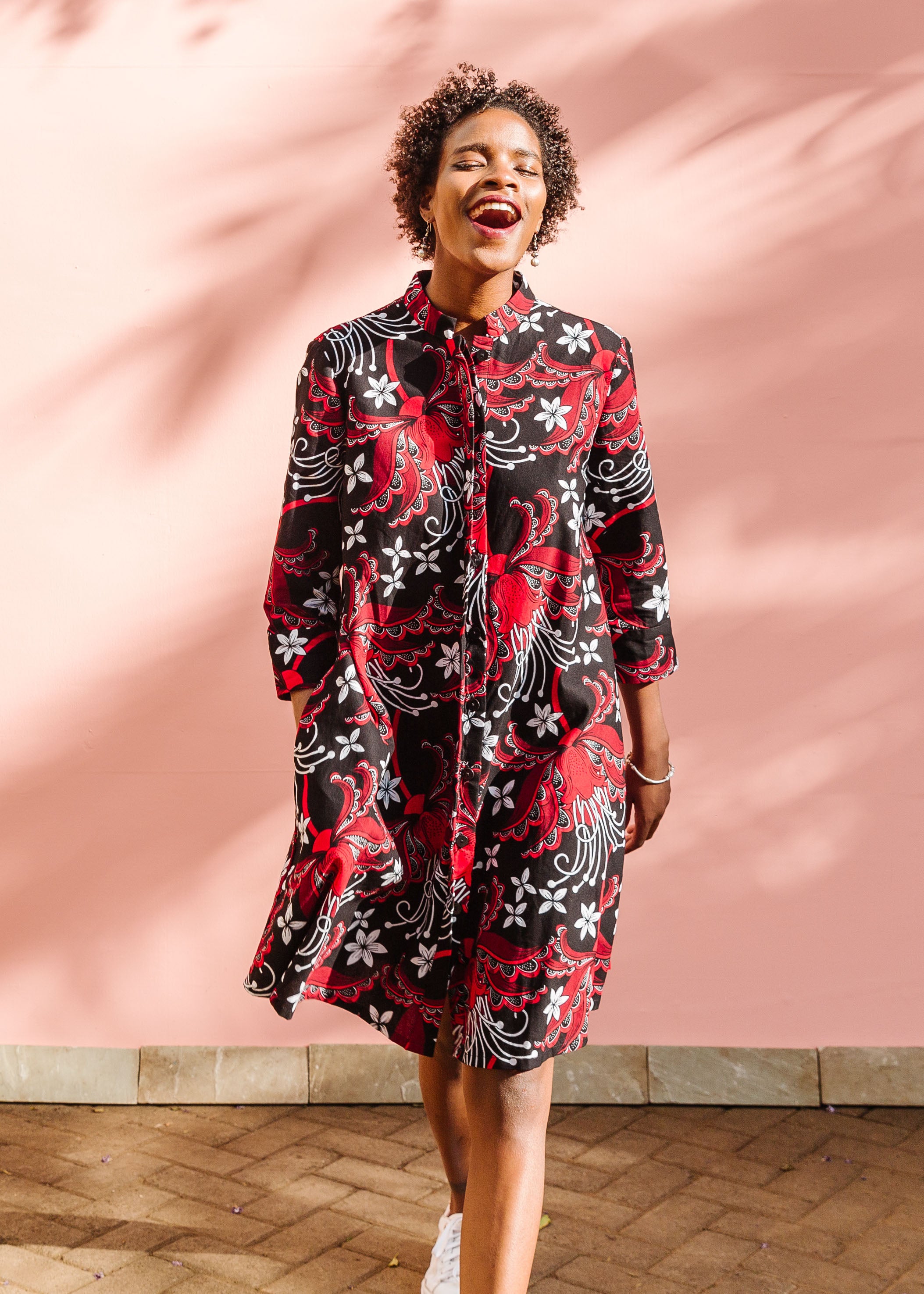 Model wearing black dress with red and white flowers.