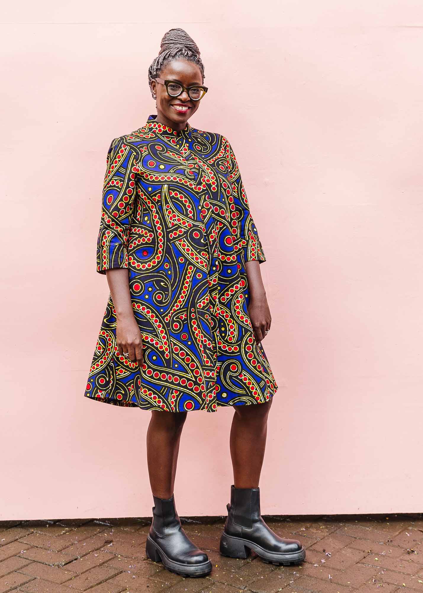 The model is wearing blue, red, black, yellow and white ornamental print dress