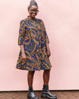 The model is wearing blue, red, black, yellow and white ornamental print dress