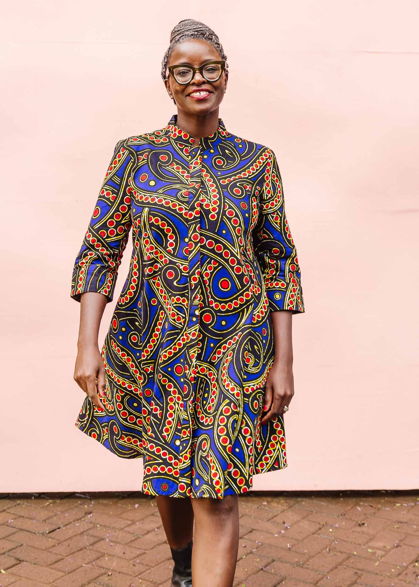 The model is wearing blue, red, black, yellow and white ornamental print dress