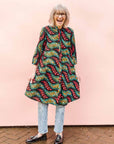 The model is wearing multicolored leaf print dress