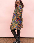 The model is wearing blue, red, black, yellow and white ornamental print dress