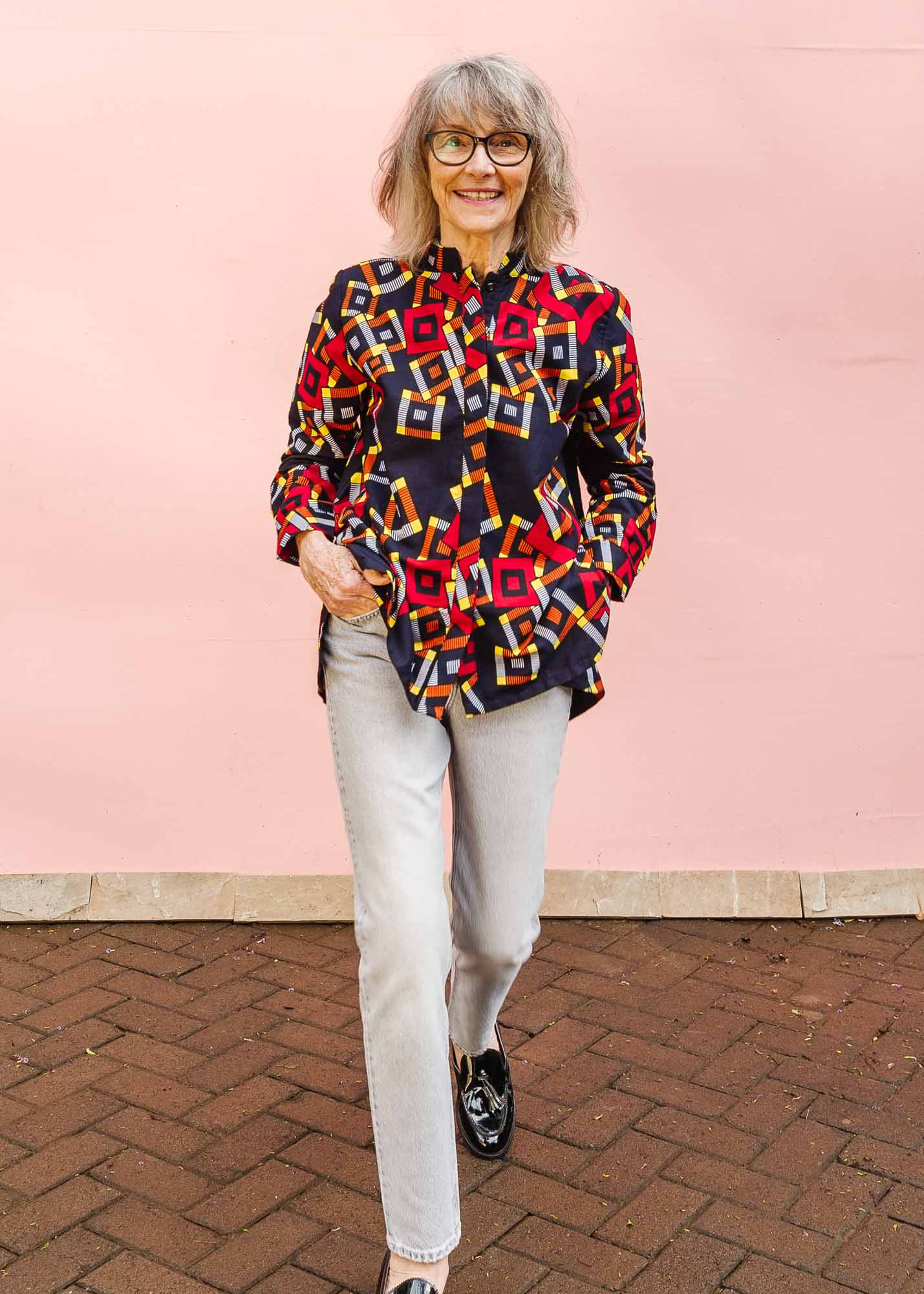 The model is wearing navy shirt with red, orange, yellow and white geometric print