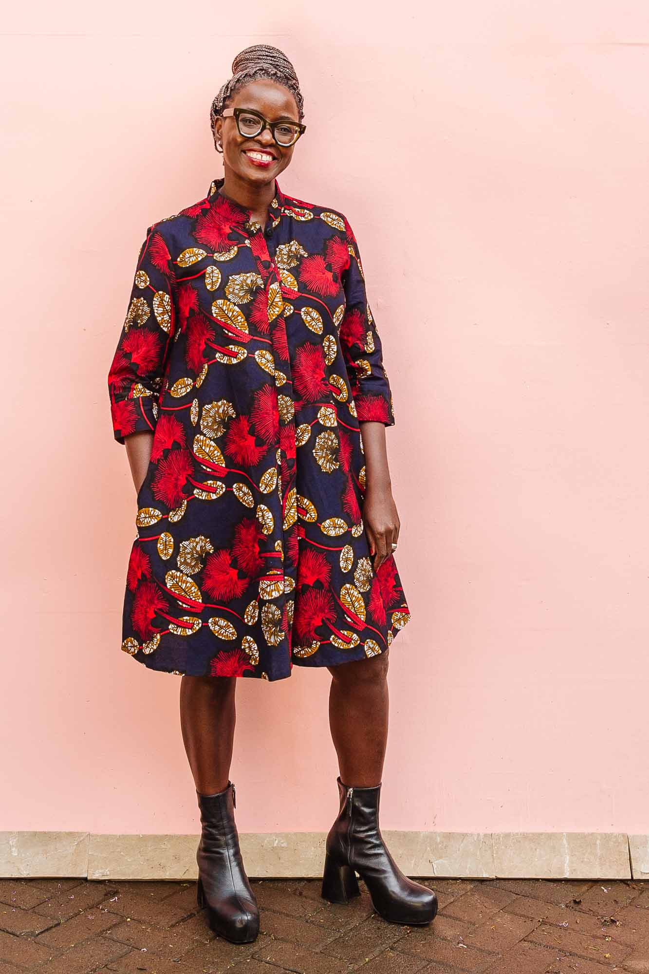 The model is wearing navy dress with red, white and orange floral print