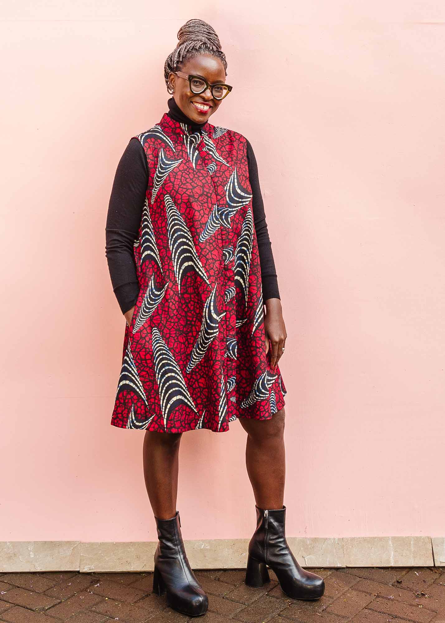 The model is wearing red and black dress with navy blue and beige print
